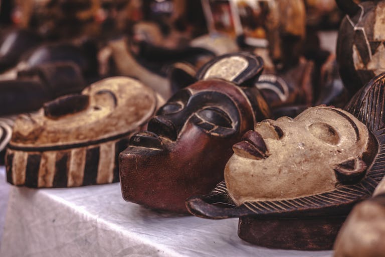 Carved wooden masks with intricate designs displayed at a vibrant market.